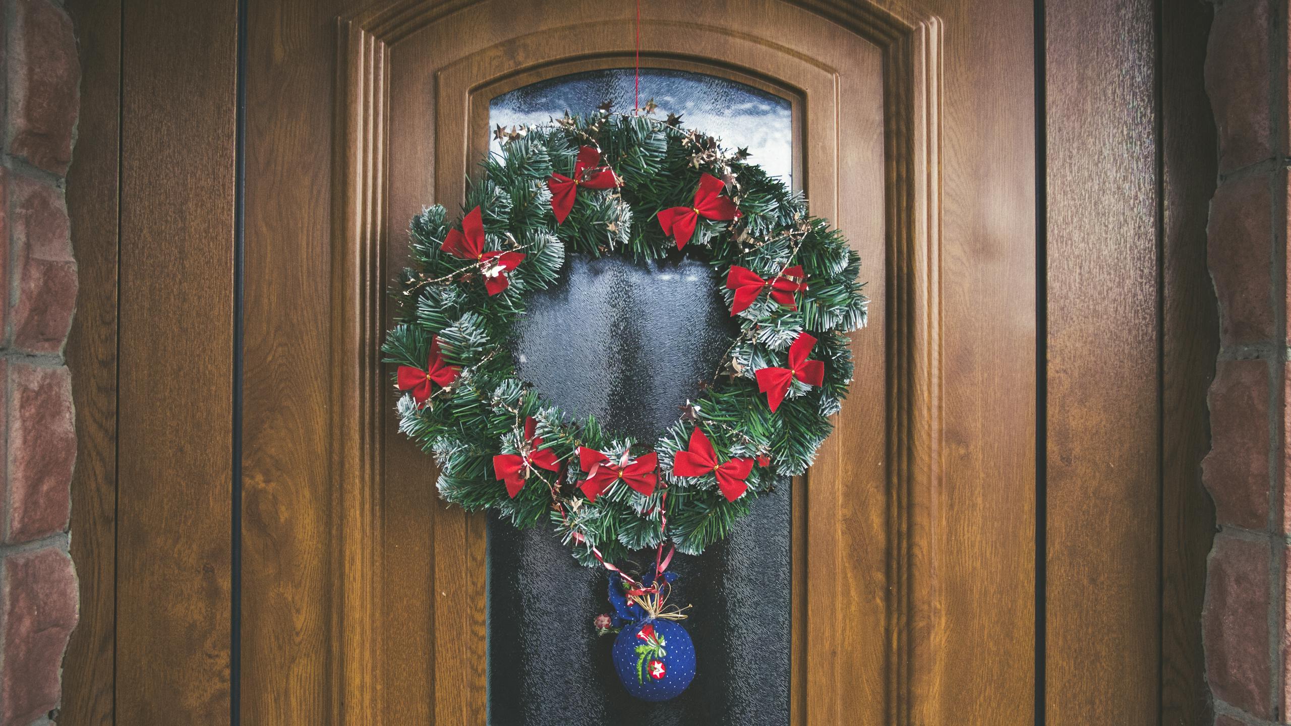 A beautifully decorated wooden door with a festive wreath and holiday ornaments.