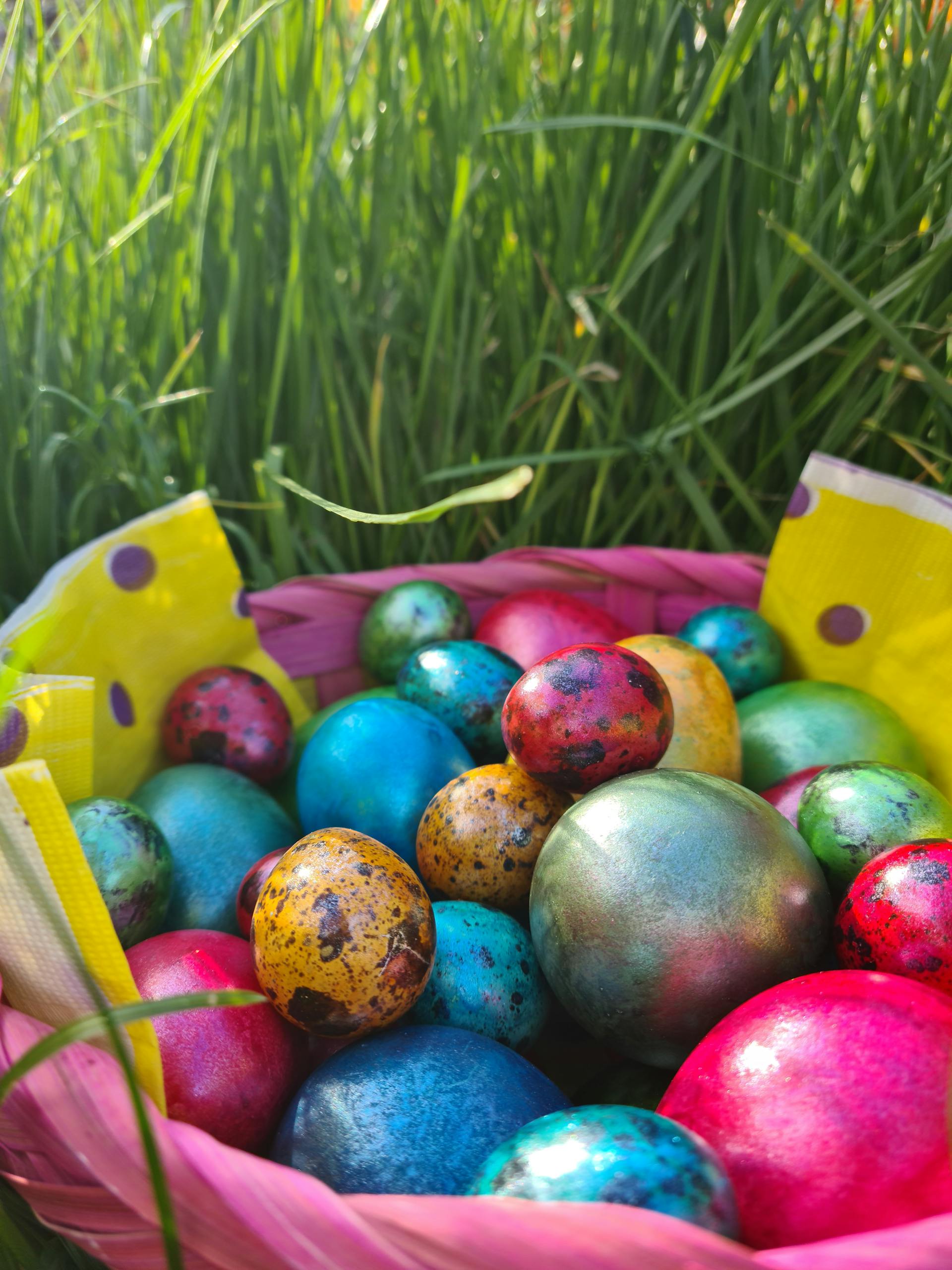 Vibrant Easter eggs in a decorative basket surrounded by lush green grass.
